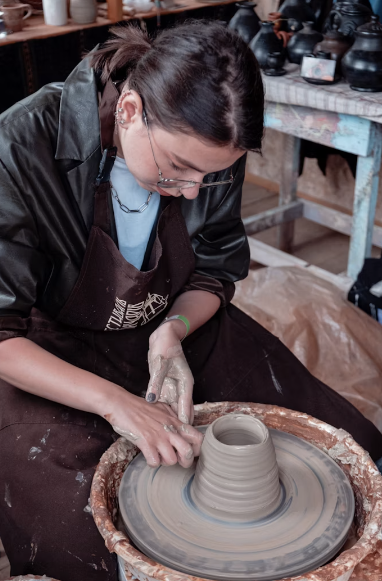 A maker shaping a bowl at the pottery wheel